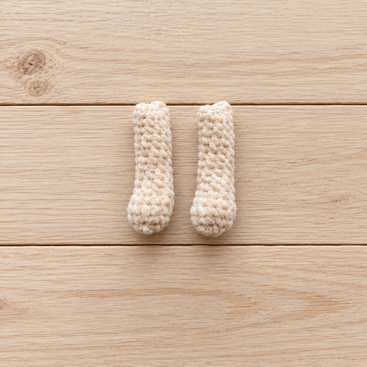 Two plush crochet bunny arms made with cream yarn
