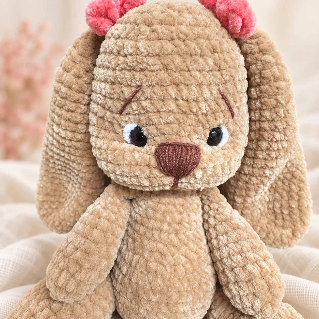 Separate floppy-eared beige crochet bunny with pink bows, shown for styling inspiration