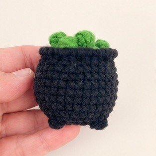 Black miniature crochet cauldron filled with green potion bubbles