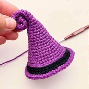 Purple crochet witch hat with a curled tip and black band